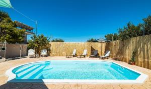 una piscina en un patio trasero con sillas y una valla en J&K HOUSE SUITES, en Aghia Marina