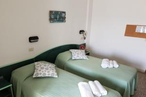 2 letti in una camera con lenzuola verdi di Hotel Concordia Palace a Rimini