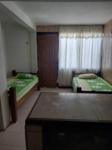 a bedroom with two beds and a window with a door at Alojamientos Nazareth in Catia La Mar