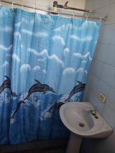 a bathroom with a sink and a shower curtain with dolphins at Alojamientos Nazareth in Catia La Mar