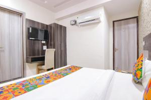 a bedroom with a white bed with a colorful blanket at HOTEL DHANUA PALACE in Chandīgarh +17 photos