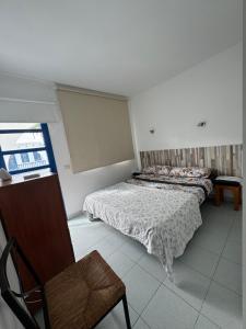 a small bedroom with two beds and a chair at 55 PLAYMAR VILLA WELLNESS in Maspalomas
