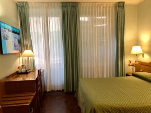 マチェラータにあるホテル アルカディアのベッド、デスク、窓が備わるホテルルームです。