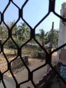 a view through a barred window of a yard at Sai sandpiper.puri in Puri