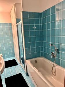 a blue tiled bathroom with a tub and a toilet at Il Portico. Charm apartment, Vicenza downtown. in Vicenza