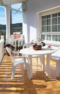 - une table blanche et 2 chaises sur une terrasse couverte dans l'établissement AG Casa Fuentes Canduas 1, à A Telleira