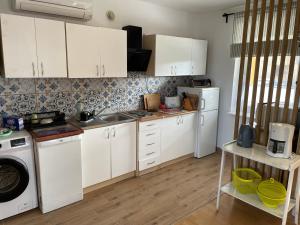 a kitchen with white cabinets and a washer and dryer at Domek wypoczynkowy Leszek in Żarnowska