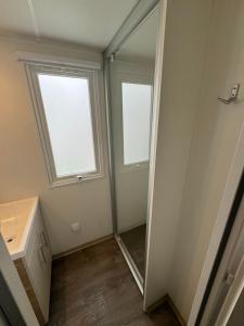 uma casa de banho com um espelho, um lavatório e 2 janelas em MH TIKE - 6p - LES SABLES DU MIDI - VALRAS em Valras-Plage