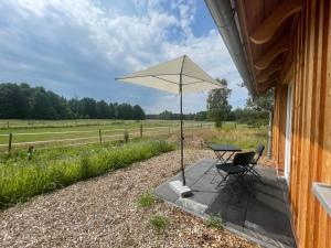 einen Tisch, einen Stuhl und einen Regenschirm auf einer Veranda in der Unterkunft Hotel TraumzeitHof in Eschede