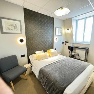 - une chambre avec un lit et une chaise dans l'établissement Cit'Hotel Les Alizes, à Dinard