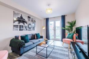 uma sala de estar com um sofá azul e uma televisão em The Belfry - Deluxe 2 Bedroom 2 Bathroom Apartment em Manchester