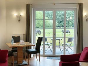 a living room with a table and chairs and elephants outside at Hotel TraumzeitHof in Eschede