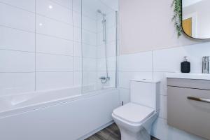 a white bathroom with a tub and a toilet at The Belfry - Deluxe 2 Bedroom 2 Bathroom Apartment in Manchester