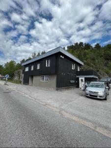 Ein schwarzes Gebäude mit einem Auto davor. in der Unterkunft Welcome to Heddalsvegen 43, Notodden's most welcoming dormitory! in Notodden