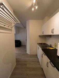 eine Küche mit weißen Schränken und einer schwarzen Arbeitsplatte in der Unterkunft Welcome to Heddalsvegen 43, Notodden's most welcoming dormitory! in Notodden