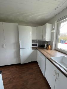 an empty kitchen with white cabinets and a window at Jyske ås in Dybvad +14 photos