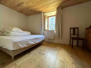 Schlafzimmer mit einem Bett mit Holzdecke und einem Fenster in der Unterkunft Mountain house with two barns and a garden in Planay