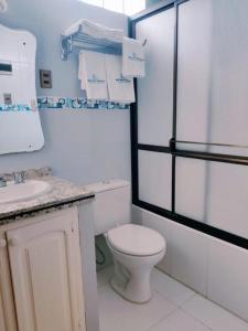 a white bathroom with a toilet and a sink at COMODORO DEPARTAMENTOS in Oruro