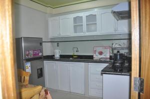 a kitchen with white cabinets and a stainless steel refrigerator at COMODORO DEPARTAMENTOS in Oruro