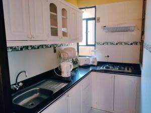 a kitchen with white cabinets and a sink at COMODORO DEPARTAMENTOS in Oruro