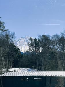 富士河口湖的住宿－ASH Villa Fujikawaguchiko，一座有积雪覆盖的山,与一座建筑相隔不远