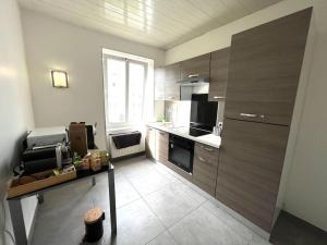 a kitchen with wooden cabinets and a table in it at Lumière Secrète Mulhouse Centre Parking Tram in Mulhouse +10 photos