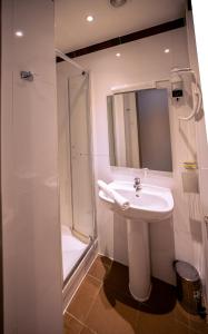a white bathroom with a sink and a shower at Hotel Aix Europe in Paris