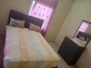 a bedroom with a bed and a dresser and a window at Costal Road hideout! in Ghana Town +11 photos