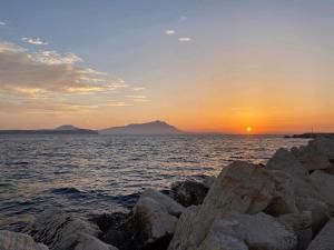 a sunset over the ocean with rocks in the foreground at Donna Cuncetta Casa Vacanza Monte di Procida in Monte di Procida
