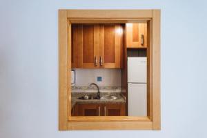 Una cocina con gabinetes de madera, un fregadero y un refrigerador. en Acogedor y central, en Sevilla 35 fotos más