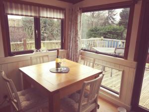 una mesa con una botella de vino en ella en una habitación con ventanas en Anne's Lodge Caerberis Holiday Park, dog friendly, en Builth Wells