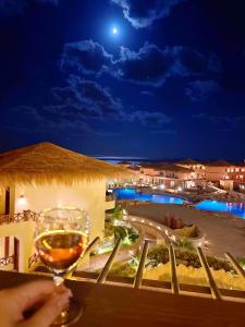 uma pessoa segurando um copo de vinho ao lado de uma piscina em Amarina Jannah Resort & Aqua Park em Coraya Bay