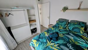 ein Schlafzimmer mit einem Bett mit einer tropisch gemusterten Decke in der Unterkunft Charmant 2p, piscine, clim, à 5 min de la plage in Vallauris