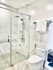 a white bathroom with a shower and a toilet at MinA Apartment - Vinhome Marina Hải Phòng in Hai Phong