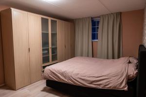 a bedroom with a bed and a cabinet and a window at Ruim vakantiehuis met mooie tuin op de Veluwe in Putten