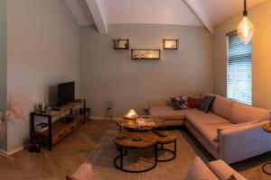 a living room with a couch and a tv at Ruim vakantiehuis met mooie tuin op de Veluwe in Putten