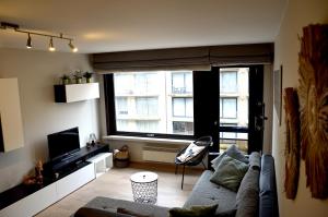 a living room with a couch and a large window at SeeYou@Sea in Nieuwpoort