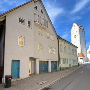un edificio blanco con puertas verdes y una torre de reloj en Ferienwohnung am Obertor en Pfullendorf