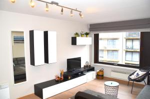 a living room with a couch and a tv on a wall at SeeYou@Sea in Nieuwpoort