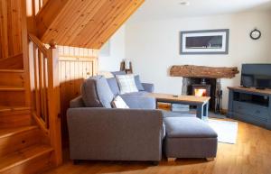 sala de estar con sofá, silla y TV en Skye Nadair, en Isleornsay