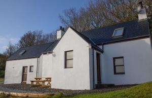 una casa blanca con una mesa de picnic delante de ella en Skye Nadair, en Isleornsay