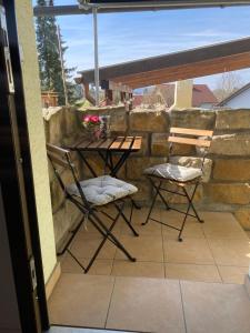 a patio with two chairs and a table on a stone wall at Ferienwohnung Fischer in Rödental in Rödental