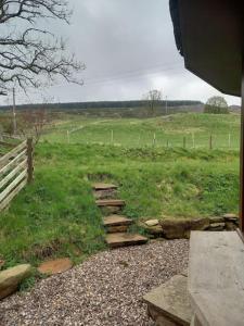 un chemin en pierre dans un champ avec une clôture dans l'établissement Lagganallachie Cottage, à Dunkeld