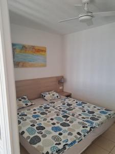 a bedroom with a bed with a floral comforter at Apartamento PinkFloyd im Palm Garden in Morro del Jable