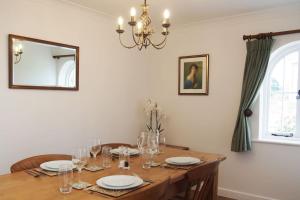 a dining room table with wine glasses and a chandelier at Stablehurst Cottage in West Hoathley