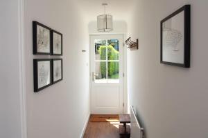a hallway with a white door and pictures on the wall at Stablehurst Cottage in West Hoathley