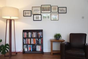 a living room with a chair and a book shelf with books at Stablehurst Cottage in West Hoathley