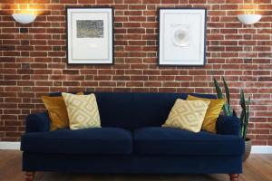 a blue couch with pillows in front of a brick wall at Stablehurst Cottage in West Hoathley