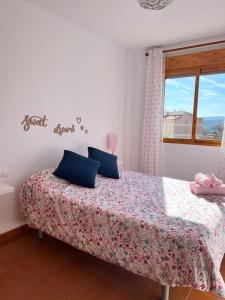 Un dormitorio con una cama con almohadas azules y una ventana en Apartamento Mezquita Caudiel, en Caudiel