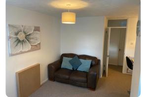 a living room with a brown leather chair with a blue pillow at One bedroom ground floor flat central Chichester in Chichester